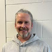 Man smiling wearing a gray sweater